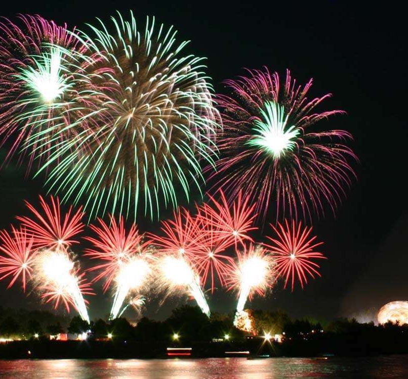 View of a city across a body of water with fireworks exploding above it
