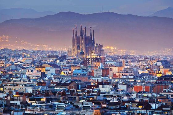 Aerial view of a sprawling cityscape with a large stone building in the distance at dusk