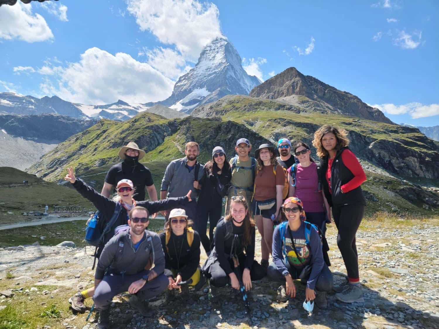 Group of travelers posing for a photo with snow-capped mountains behind them.