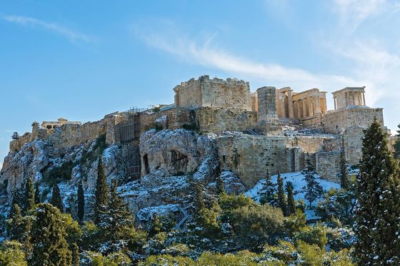 Ruins of an ancient temple on a hill dusted with snow on a sunny day
