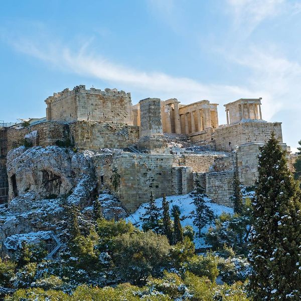 Ruins of an ancient temple on a hill dusted with snow on a sunny day