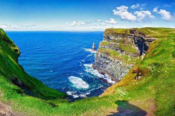 A sharp grass-covered cliff at the edge of the sea