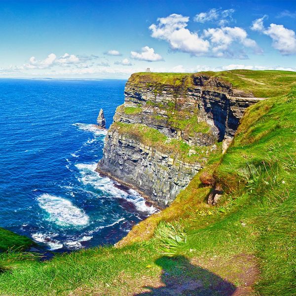A sharp grass-covered cliff at the edge of the sea