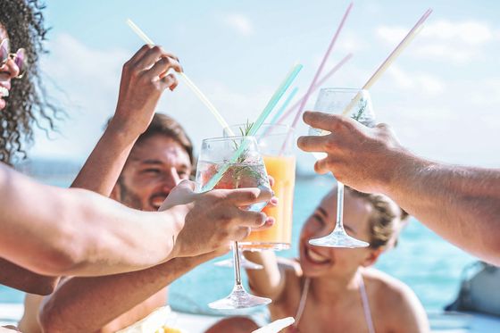 Four young people on a boat toasting with drinks