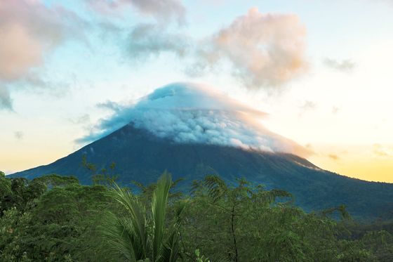 Distant view of a volcano with its peak shrouded in clouds