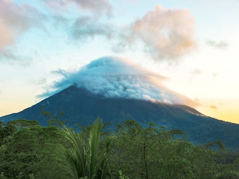 Distant view of a volcano with its peak shrouded in clouds