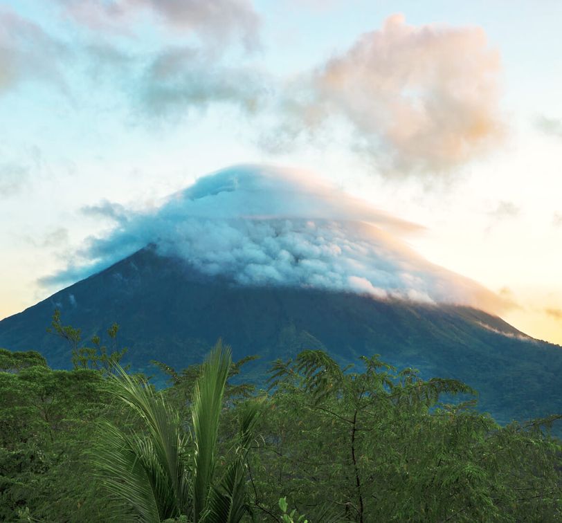 Distant view of a volcano with its peak shrouded in clouds