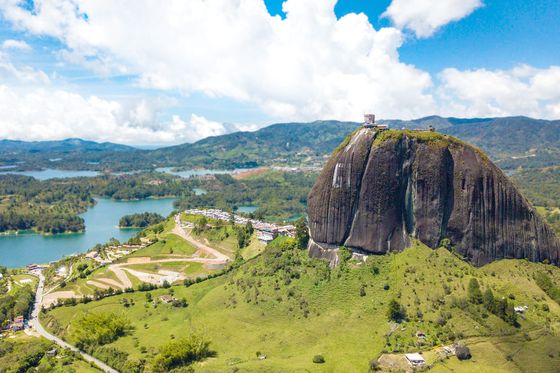 A large rock mountain overlooking green land and water