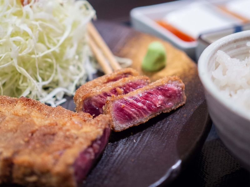A plate of meat and a bowl of rice on a table