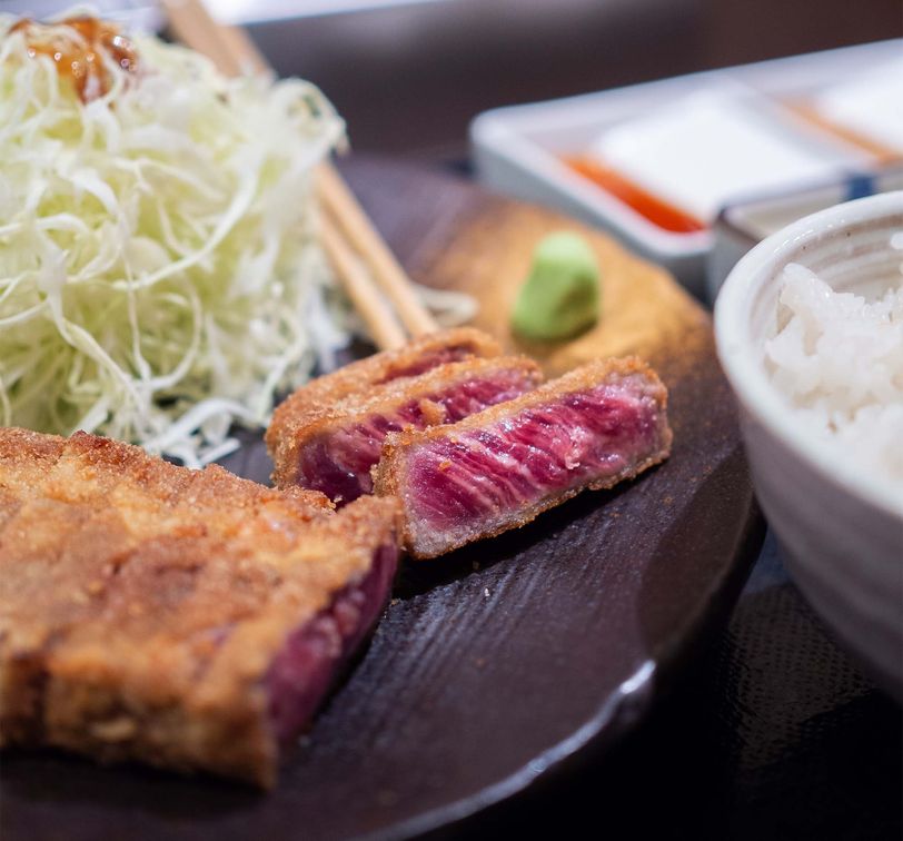 A plate of meat and a bowl of rice on a table