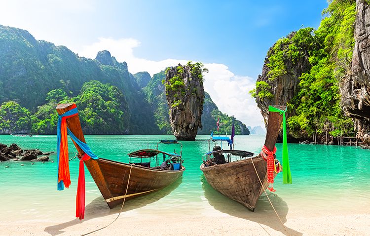 Two wooden boats on the shoreline of a bay surrounded by cliffs