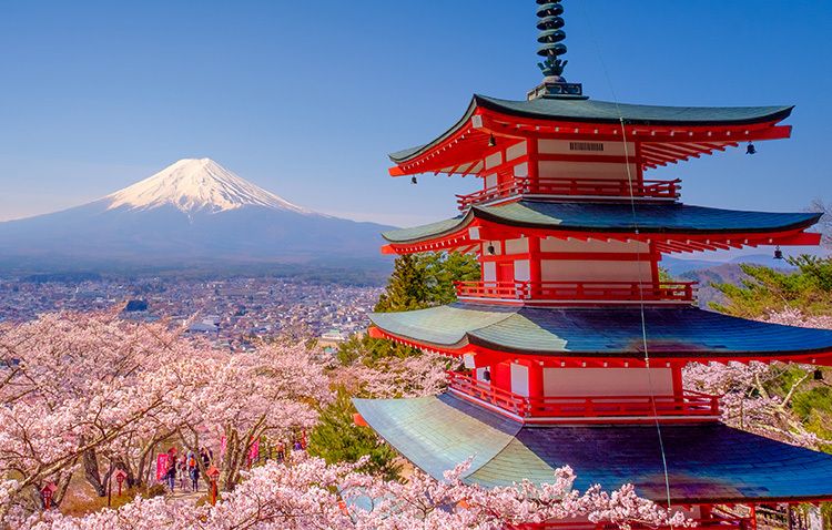 A red temple overlooking a city and a volcano in the distance