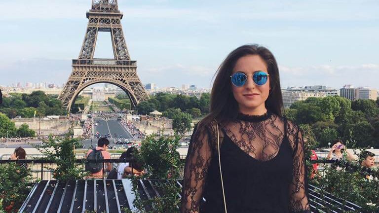 A woman standing in front of the Eiffel Tower in Paris, France.