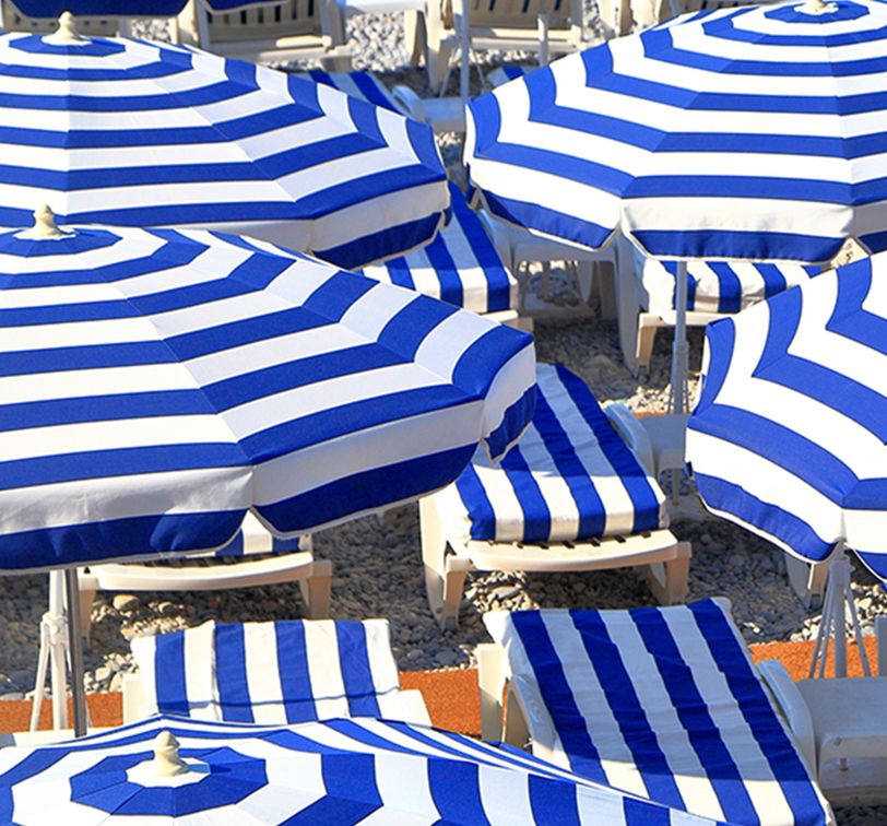 Close up of blue and white striped umbrellas on beach