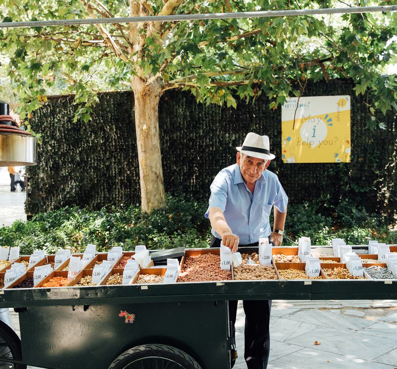 a street vendor selling nuts from his cart on a sunny day