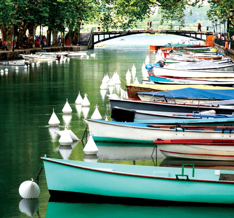 colorful canoes docked in canal with people walking by