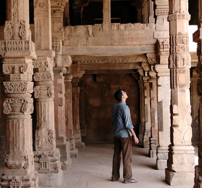 traveler looking up at the qutub minar in new delhi