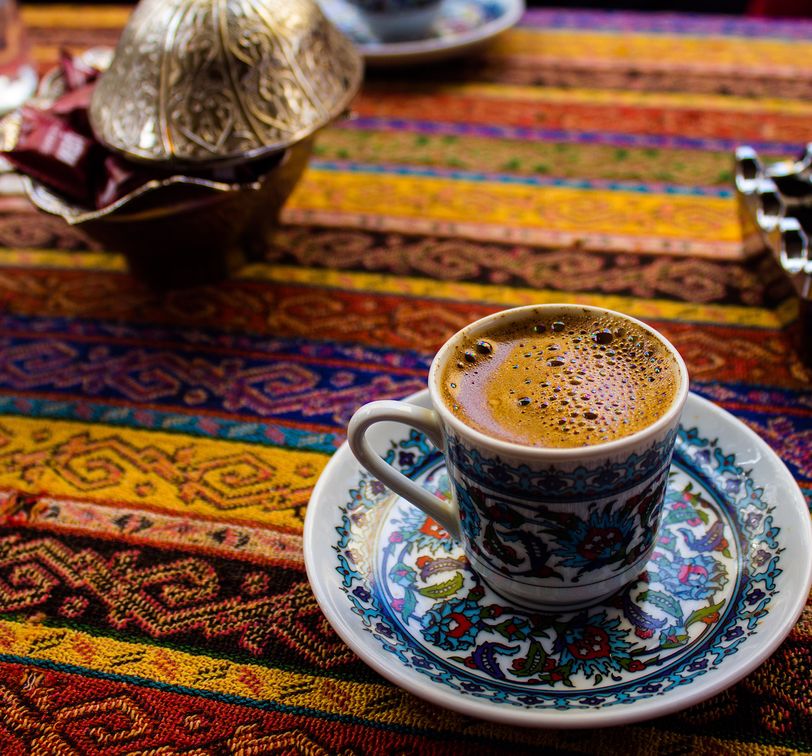 blue saucer with a cup of turkish coffee on a multicolored tablecloth