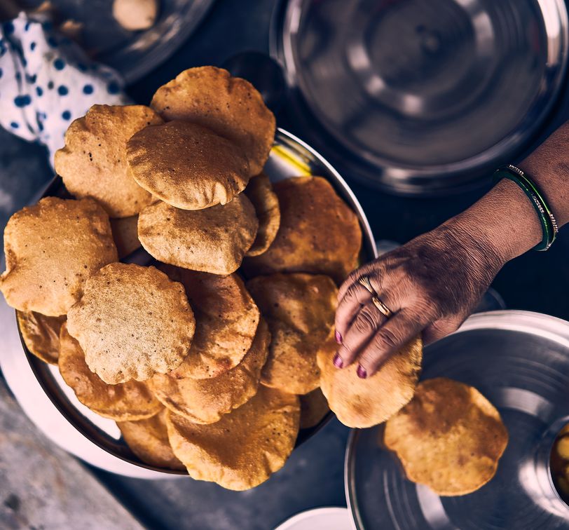 hand of a woman serving fried indian bread called poori