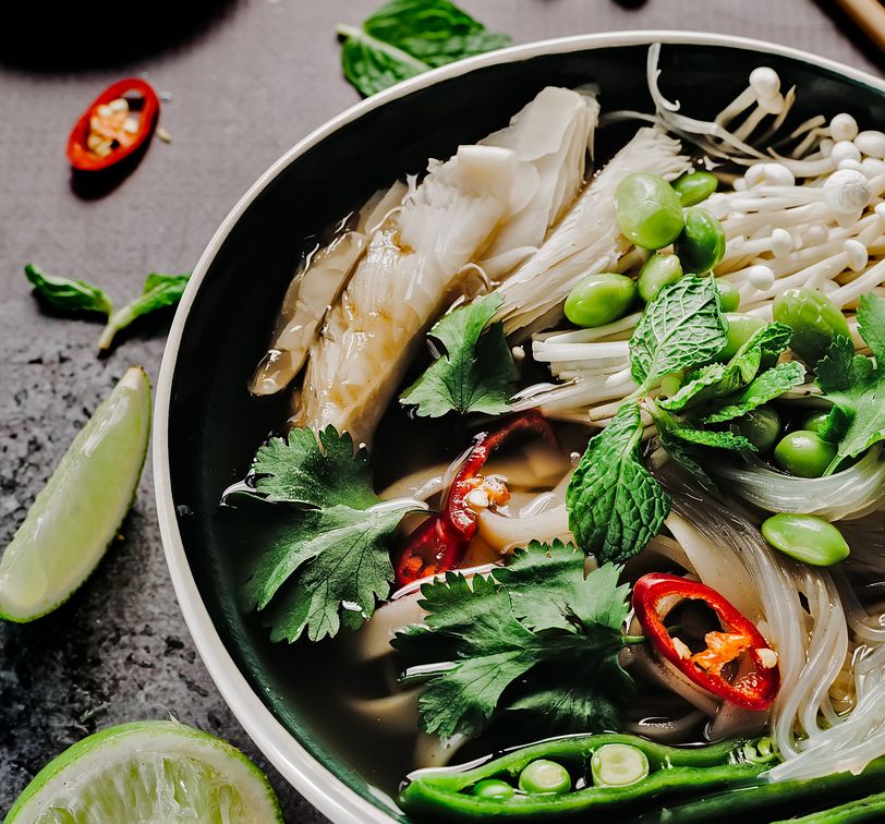 a bowl of vietnamese noodle soup with vegetables called pho