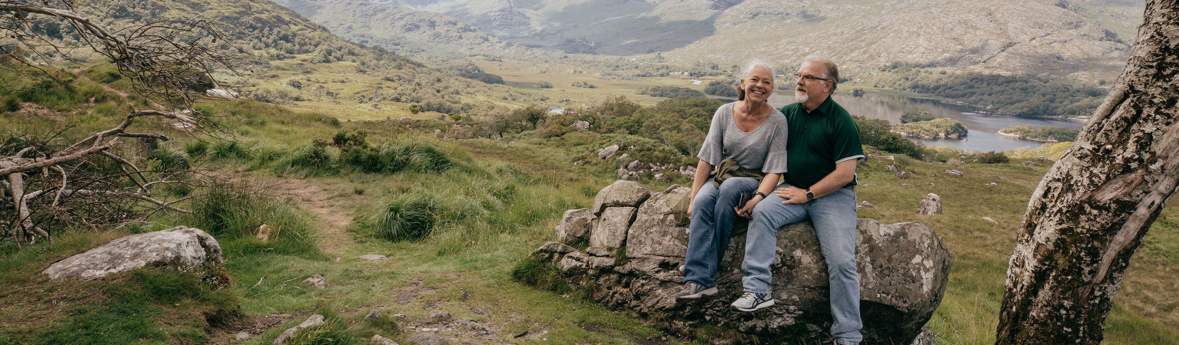 couple of travelers sitting a on a rock in ireland together