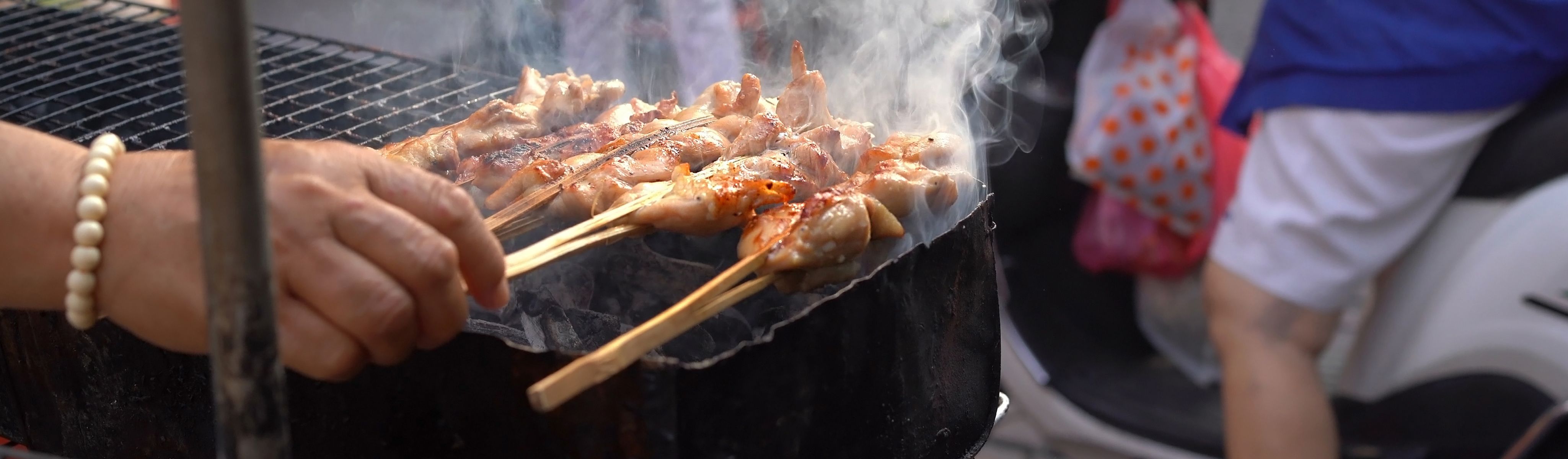 hand cooking chicken on the grill