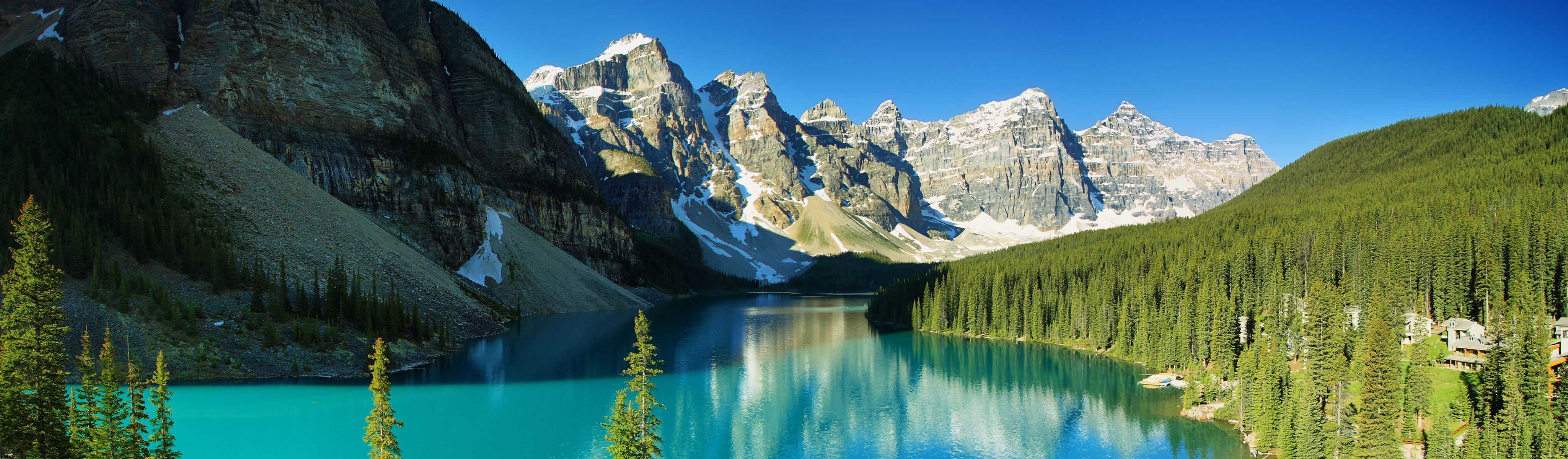 snow capped canadian rockies mountains surrounding bright teal lake and evergreen trees