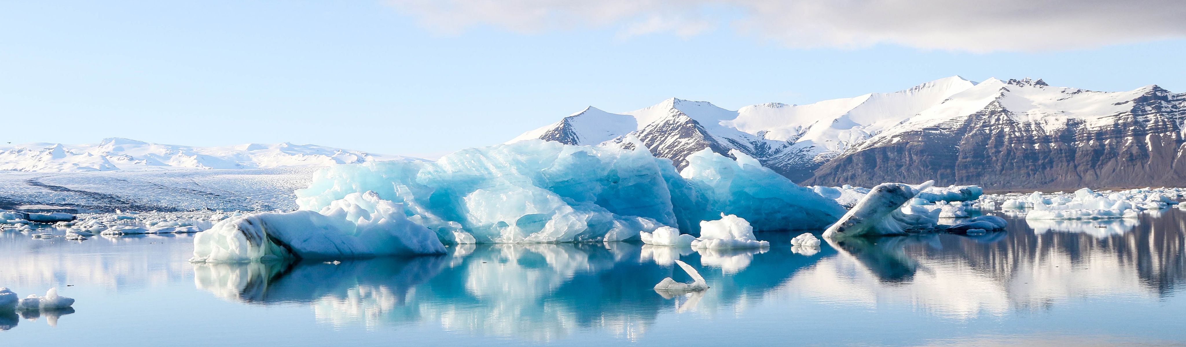 bright blue icebergs floating in a lagoon in iceland surrounded by snowcapped mountains