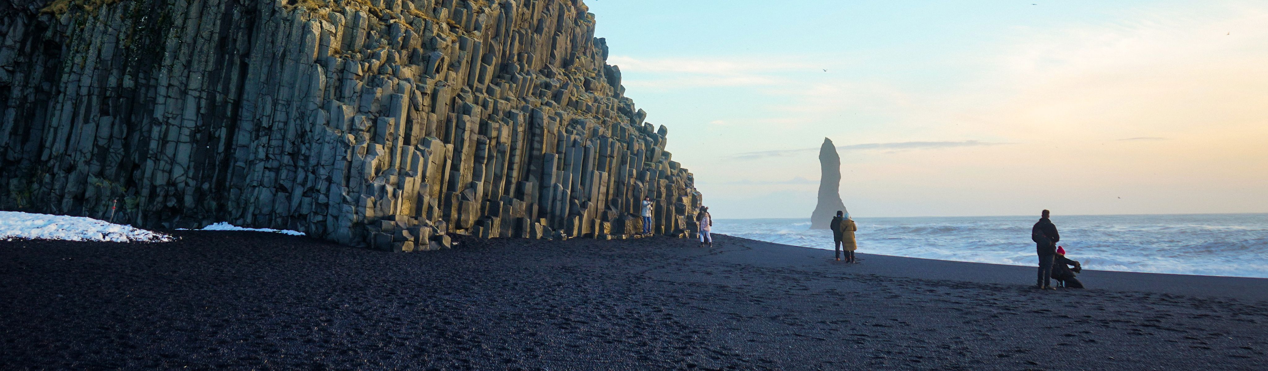 people walking on black sand beach in iceland