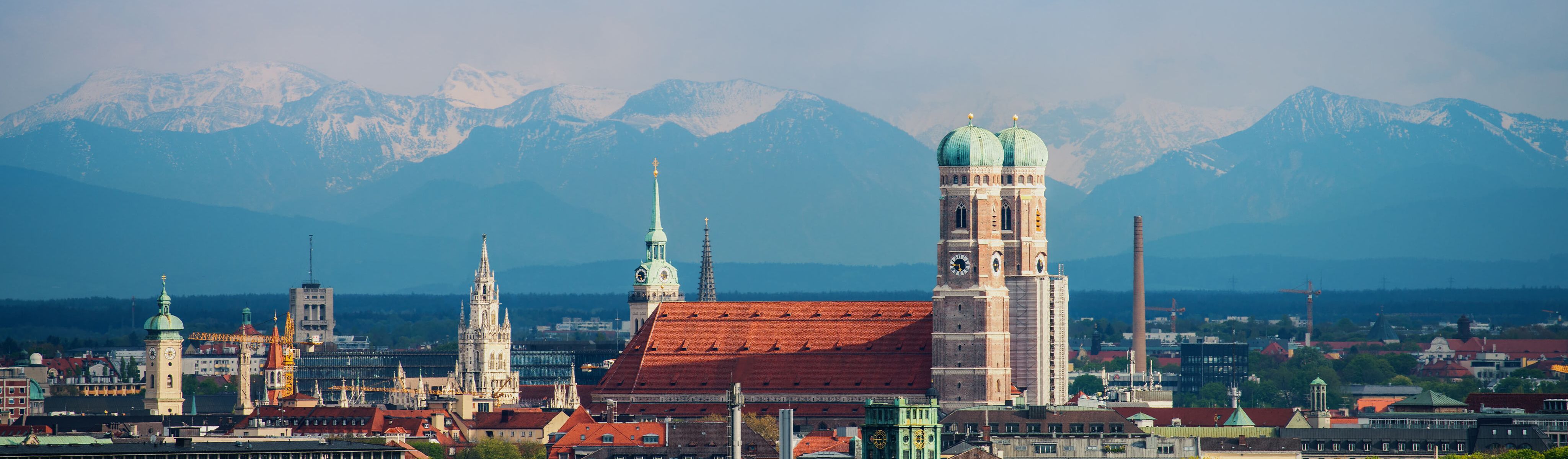 green domed building surrounded by snow capped mountains in munich germany