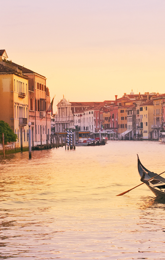 venetian gondolier riding on gondola through canal in venice italy