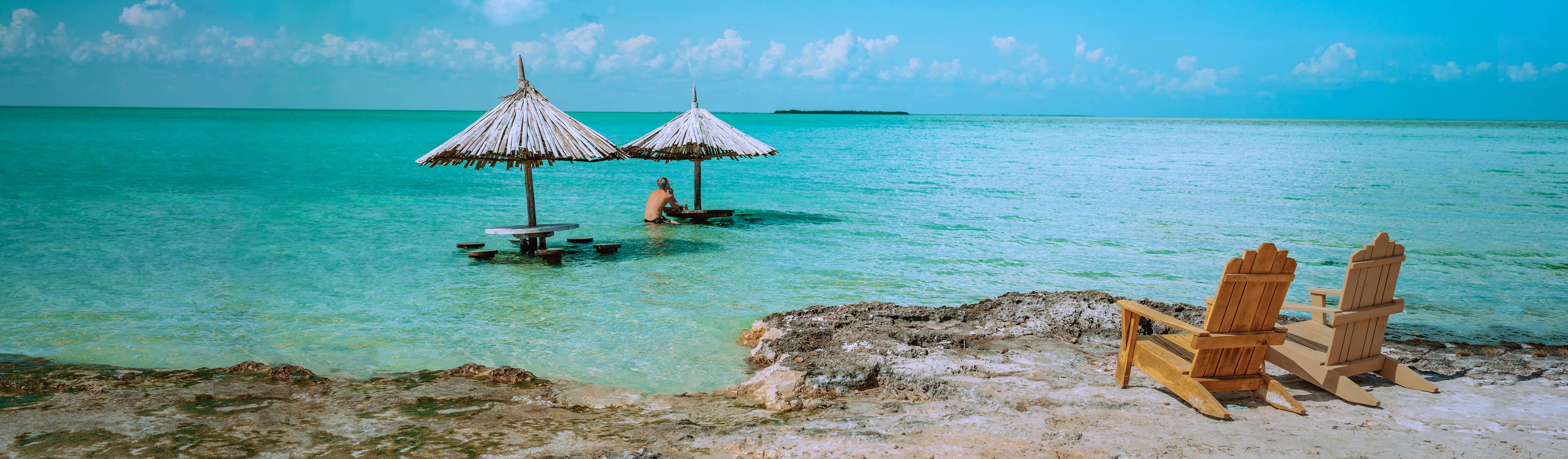 man sitting at a tiki table in the ocean off the coast of Belize