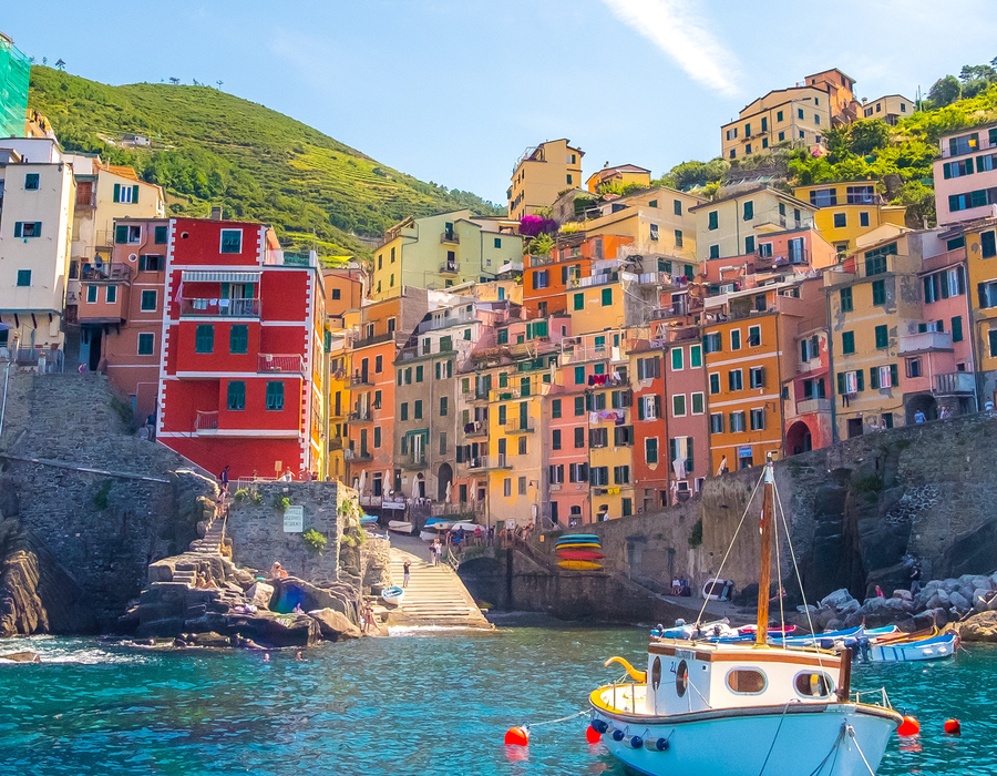 boats in the marina with people walking along wall in cinque terre italy