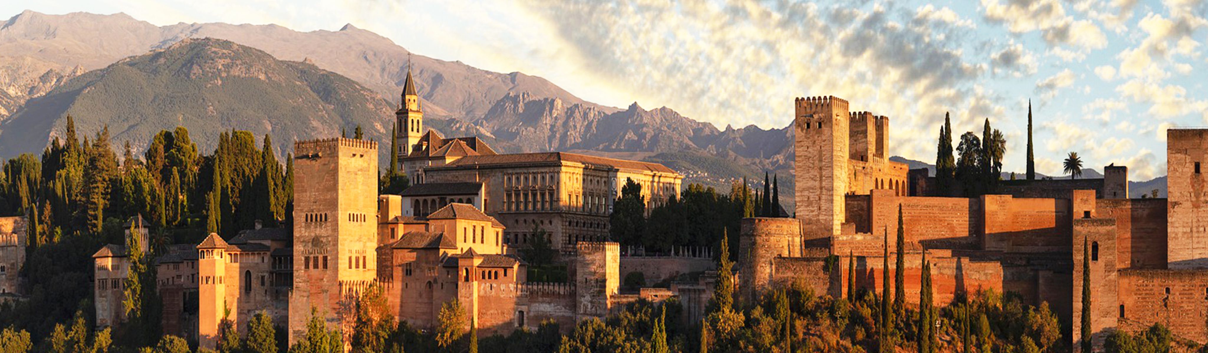 sun shining on stone buildings in granada spain surrounded by mountains