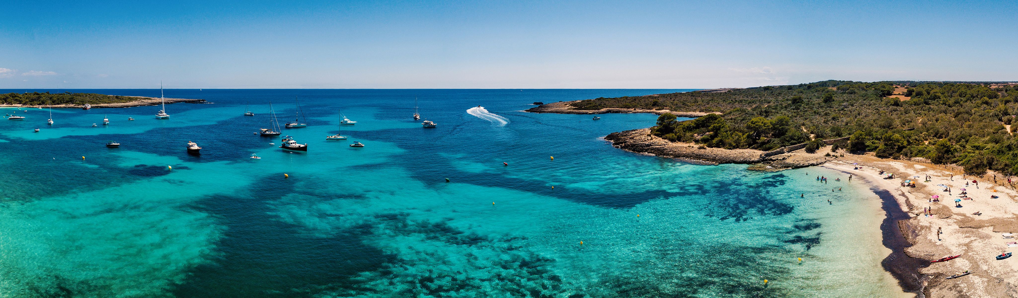 boats docked in the crystal blue water off the coast of Menorca in Spain