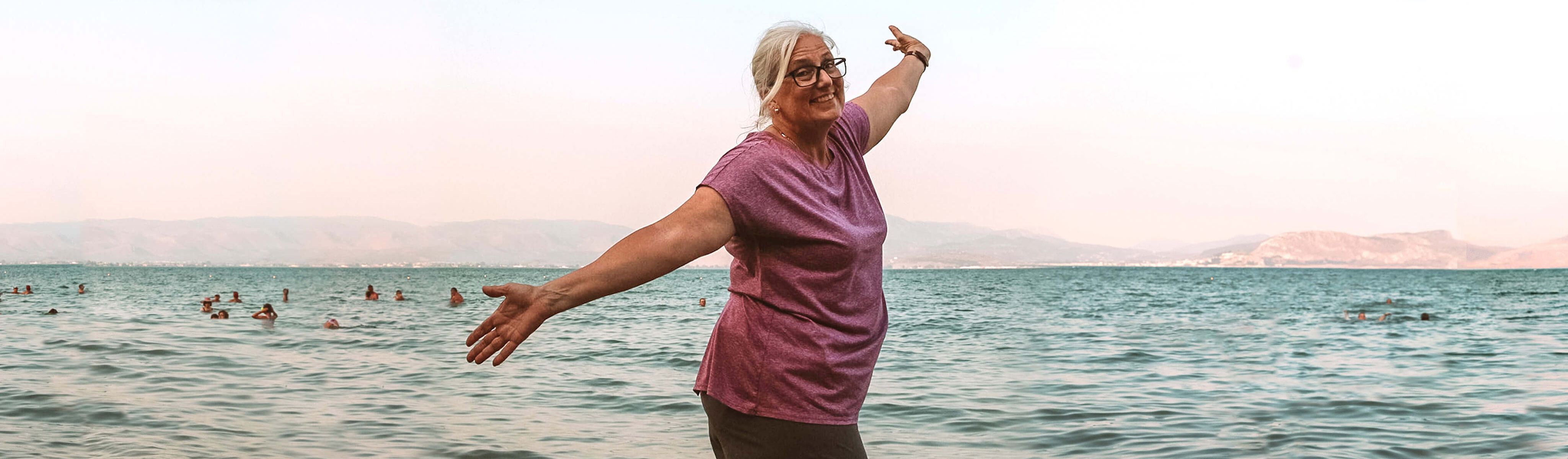 woman hands in the air at the beach in nafplio in greece