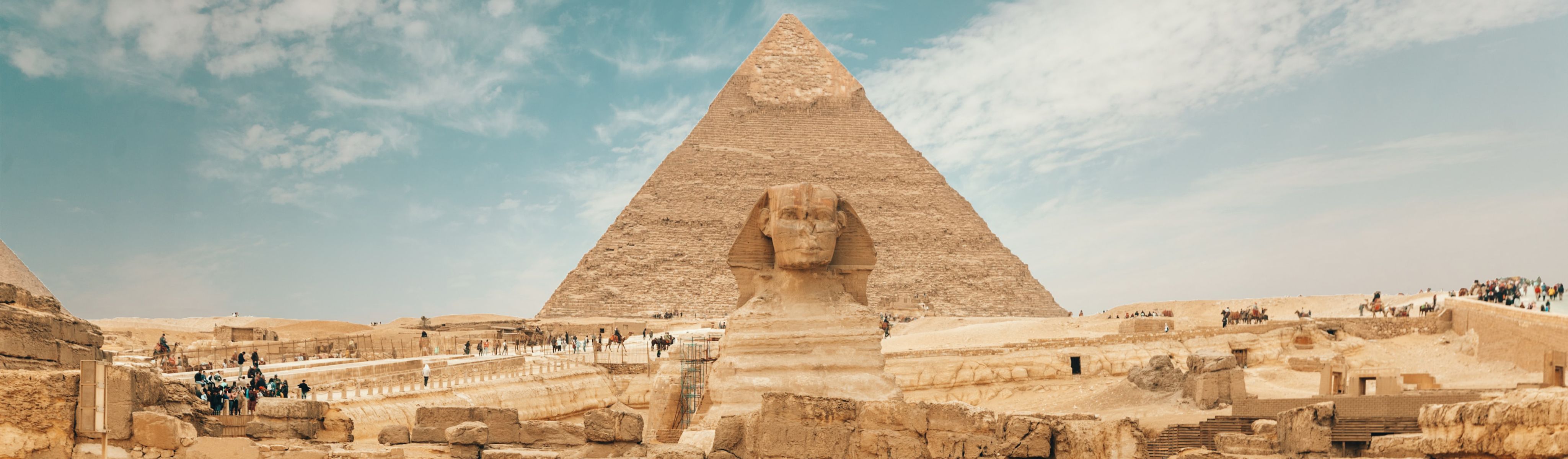 people walking around the pharaoh sculpture in front of the pyramids in egypt