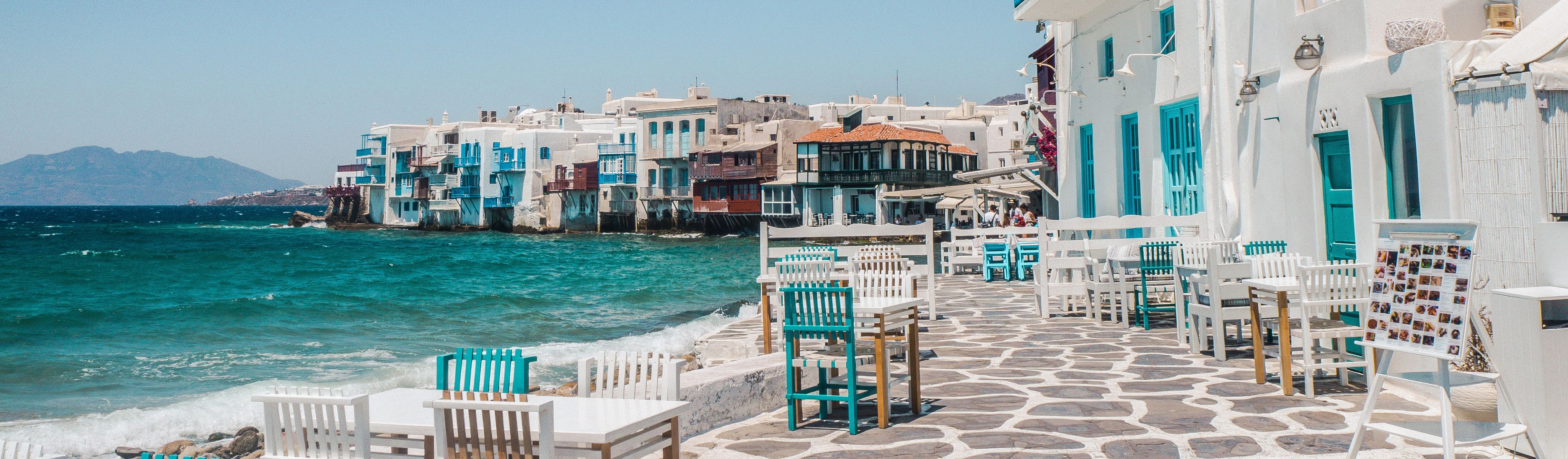 blue and white chairs lined along a cobblestone walk way outside a restaurant in Greece