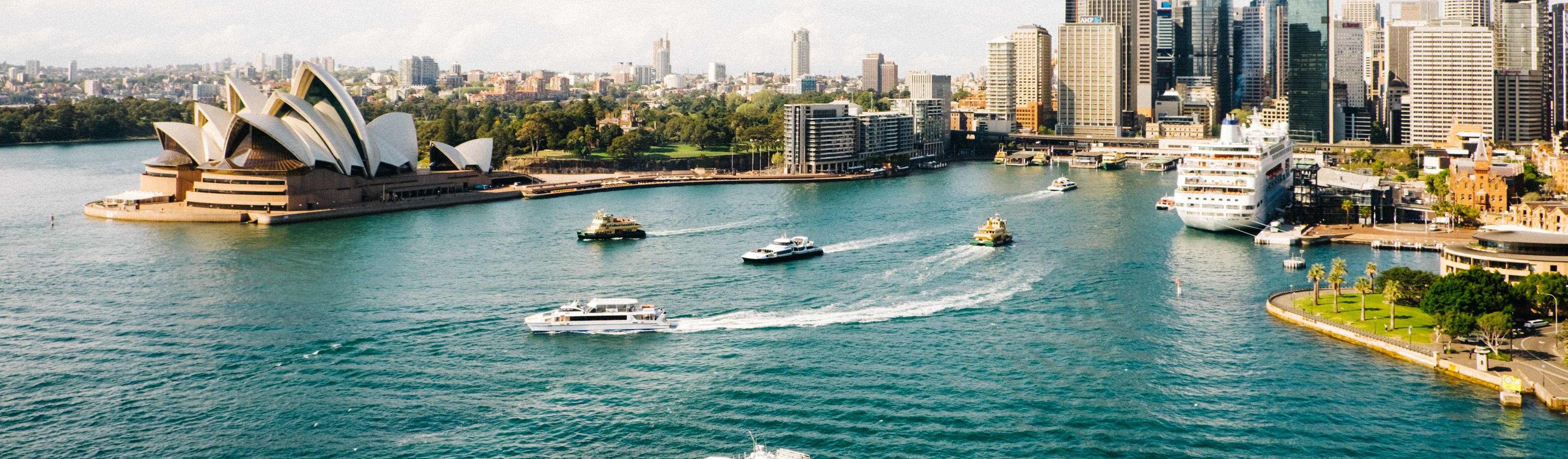 boats riding through water near opera house in sydney australia