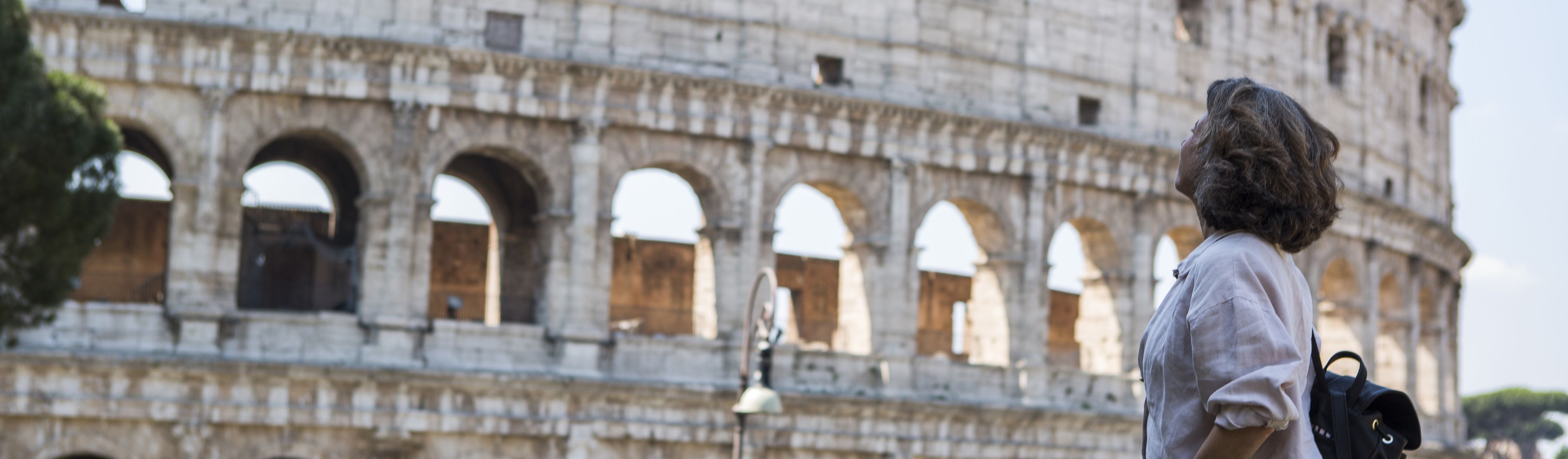 female solo traveler looking up at the colosseum in rome italy 