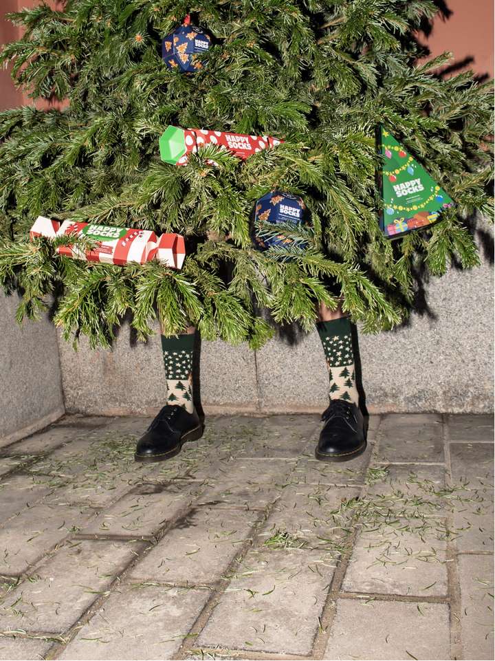 A Christmas tree on human legs filled with Happy Socks gift sets. 