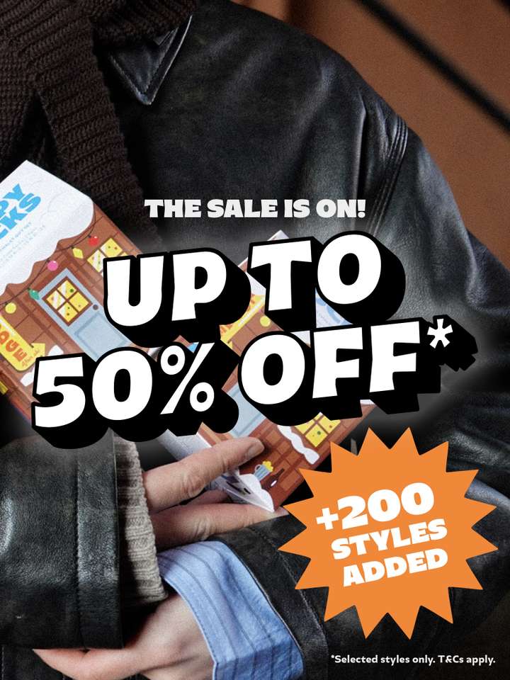 A person wearing a leather jacket, holding Happy Socks gift boxes. The text reads 'The Sale is On! Up to 50% OFF* +200 Styles Added'