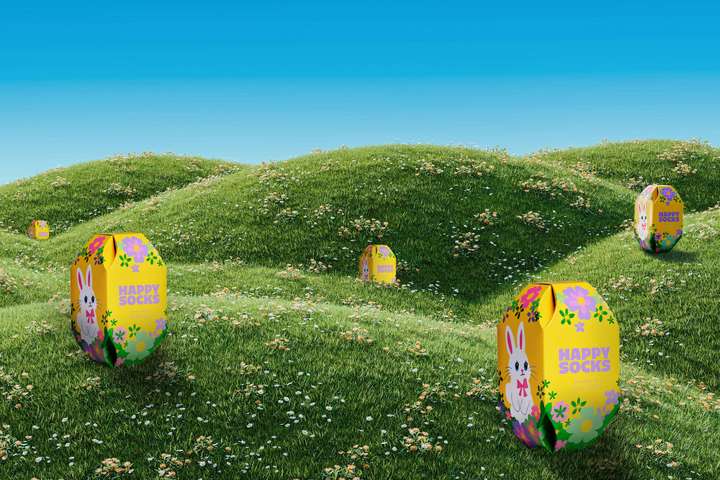 Ein Paar Beine vor beigem Hintergrund. Die Beine tragen ein Paar blaue Happy Socks mit einem Aufdruck aus weißen Hasen.