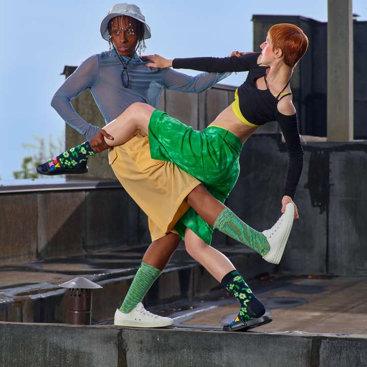 Two people happily dancing. They're both wearing alternative and energetic outfits, complete with Happy Socks.