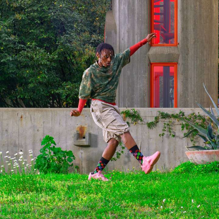 A person happily dancing in a garden, wearing black Happy Socks featuring colorful peace signs