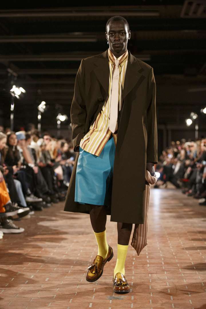 A man walking on the runway wearing yellow happy socks