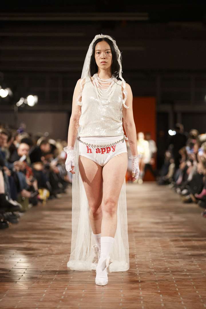 a person walking the runway in a full white outfit, including white happy socks.