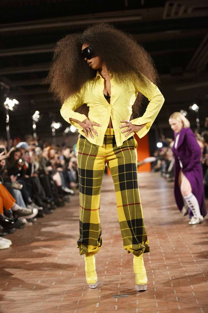 a person posing on the runway, wearing a full yellow outfit, including the socks