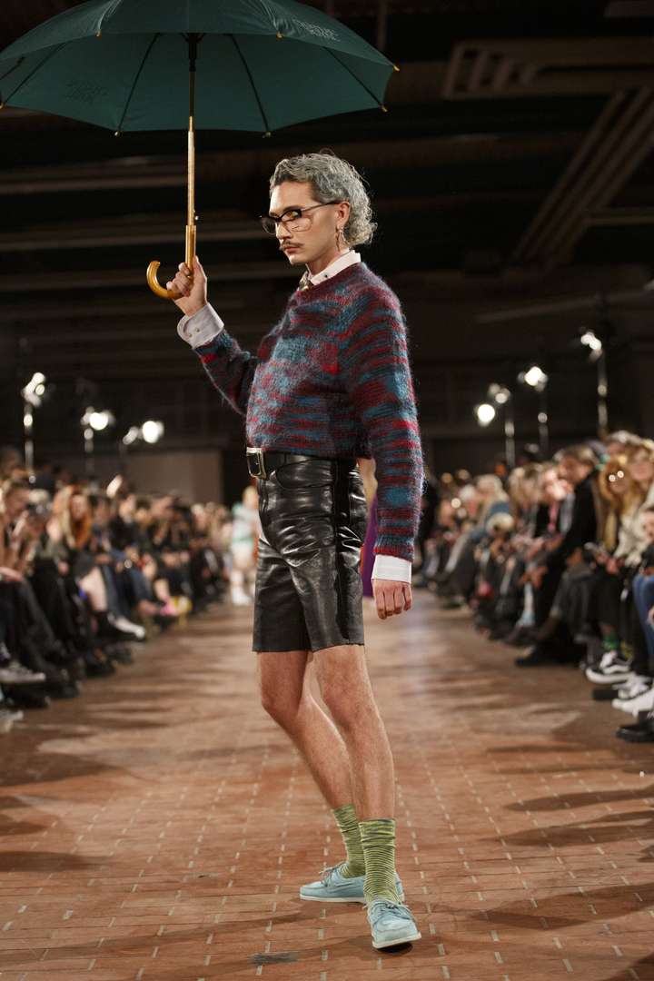 A person walking on the runway, wearing green happy socks.