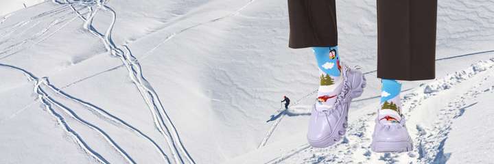 Ski slopes landscape with a pair of legs superimposed on top wearing winter style Happy Socks.